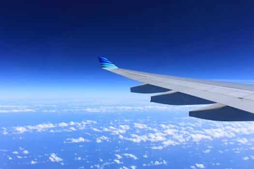 Scenic view of an airplane wing flying high above the clouds on a clear day.